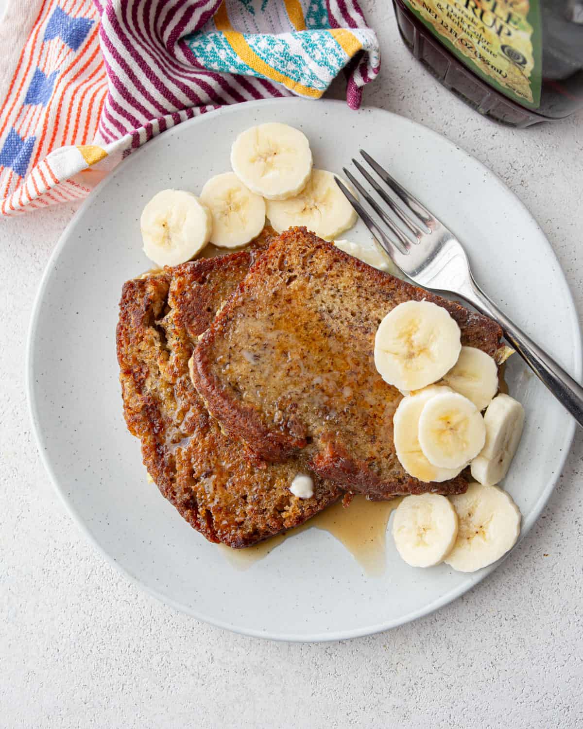 two slices of banana bread french toast on a white plate