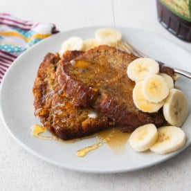 two pieces of banana bread french toast on a white plate