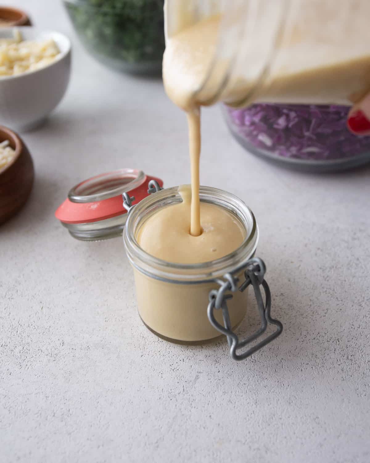 pouring tahini dressing into a small glass jar