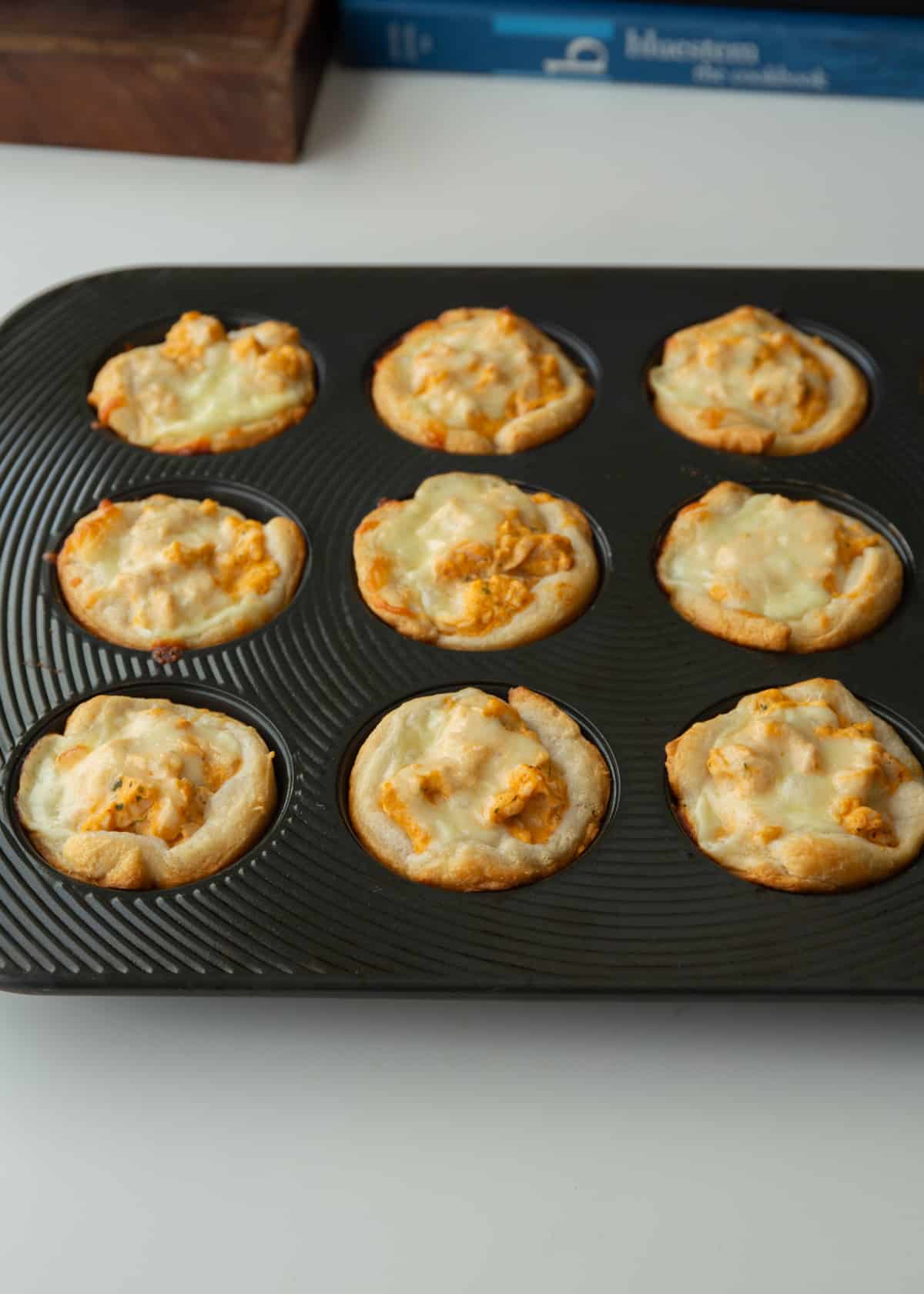 cooked buffalo chicken dip bites in a muffin tin