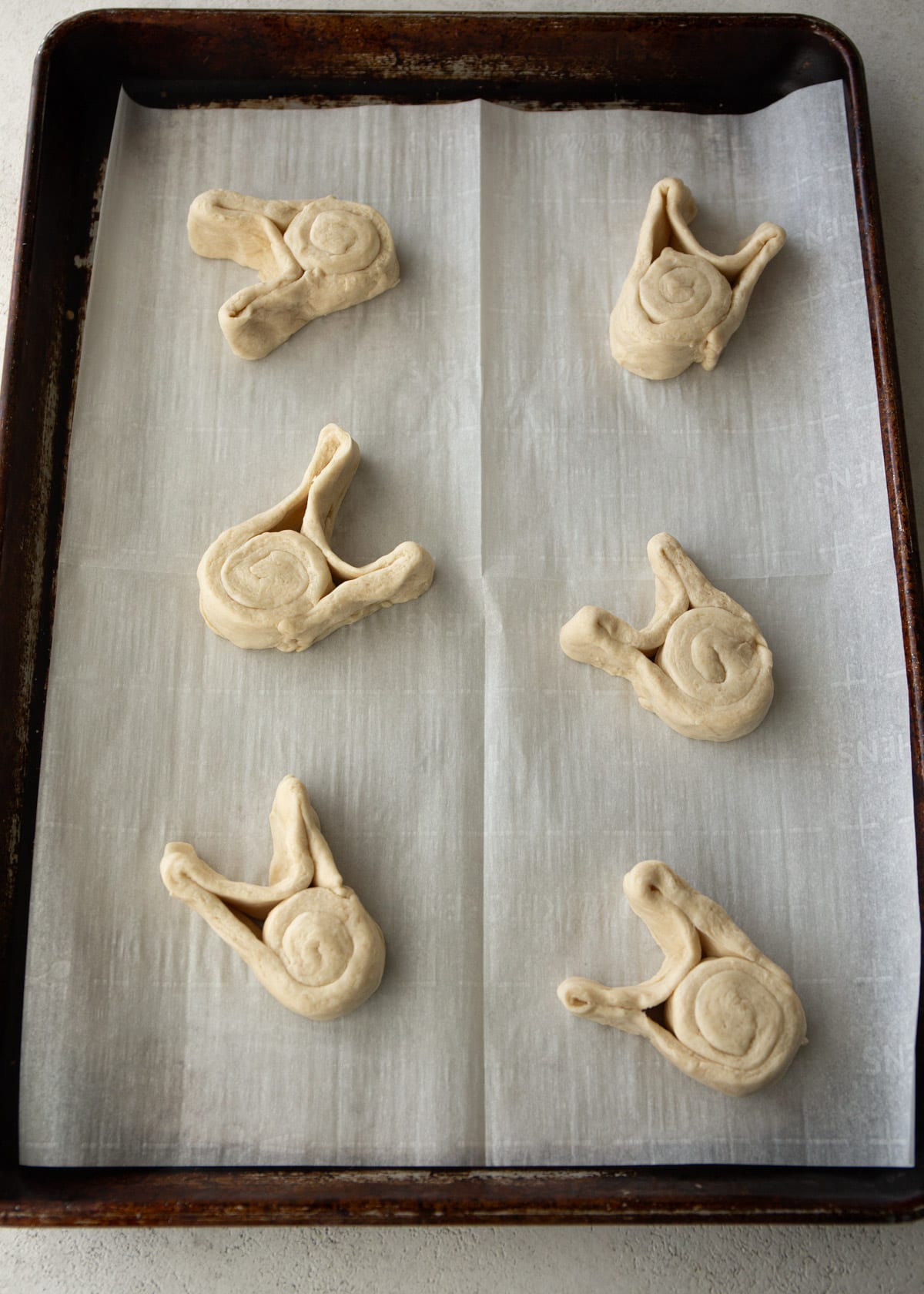 uncooked bunny shaped rolls on a parchment lined sheet pan