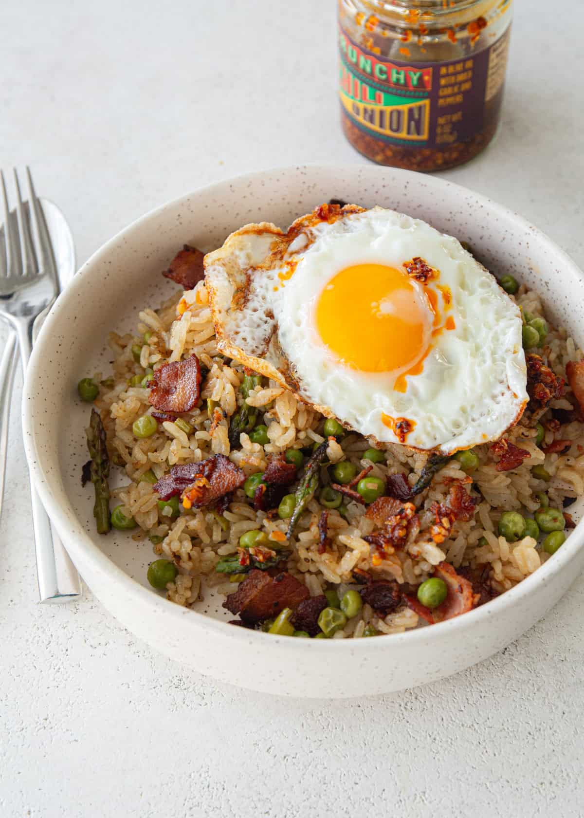 bacon fried rice topped with a fried egg in a white bowl