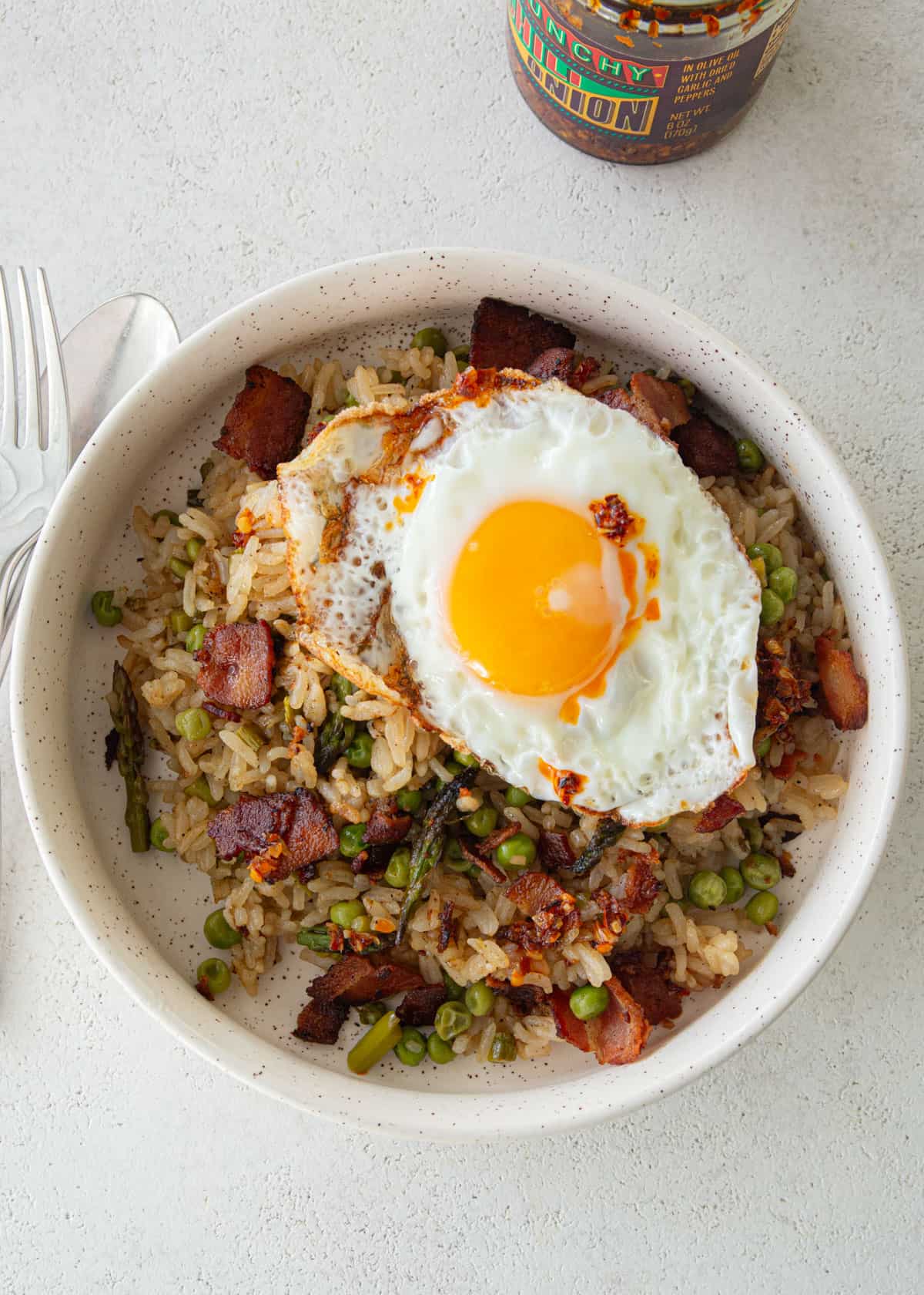 overhead image of bacon fried rice in a white bowl on a white countertop
