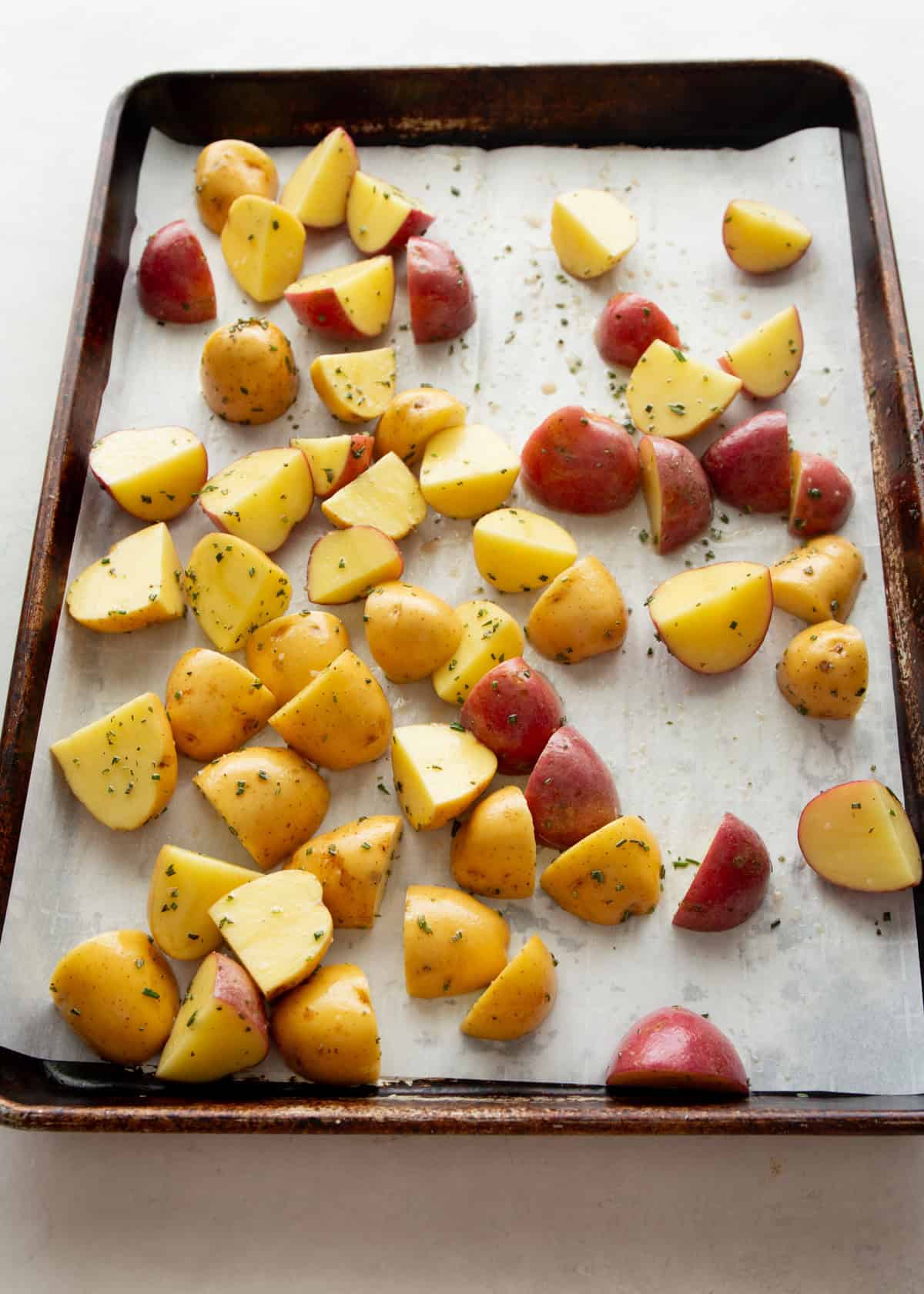 quartered red potatoes on a parchment lined sheet pan