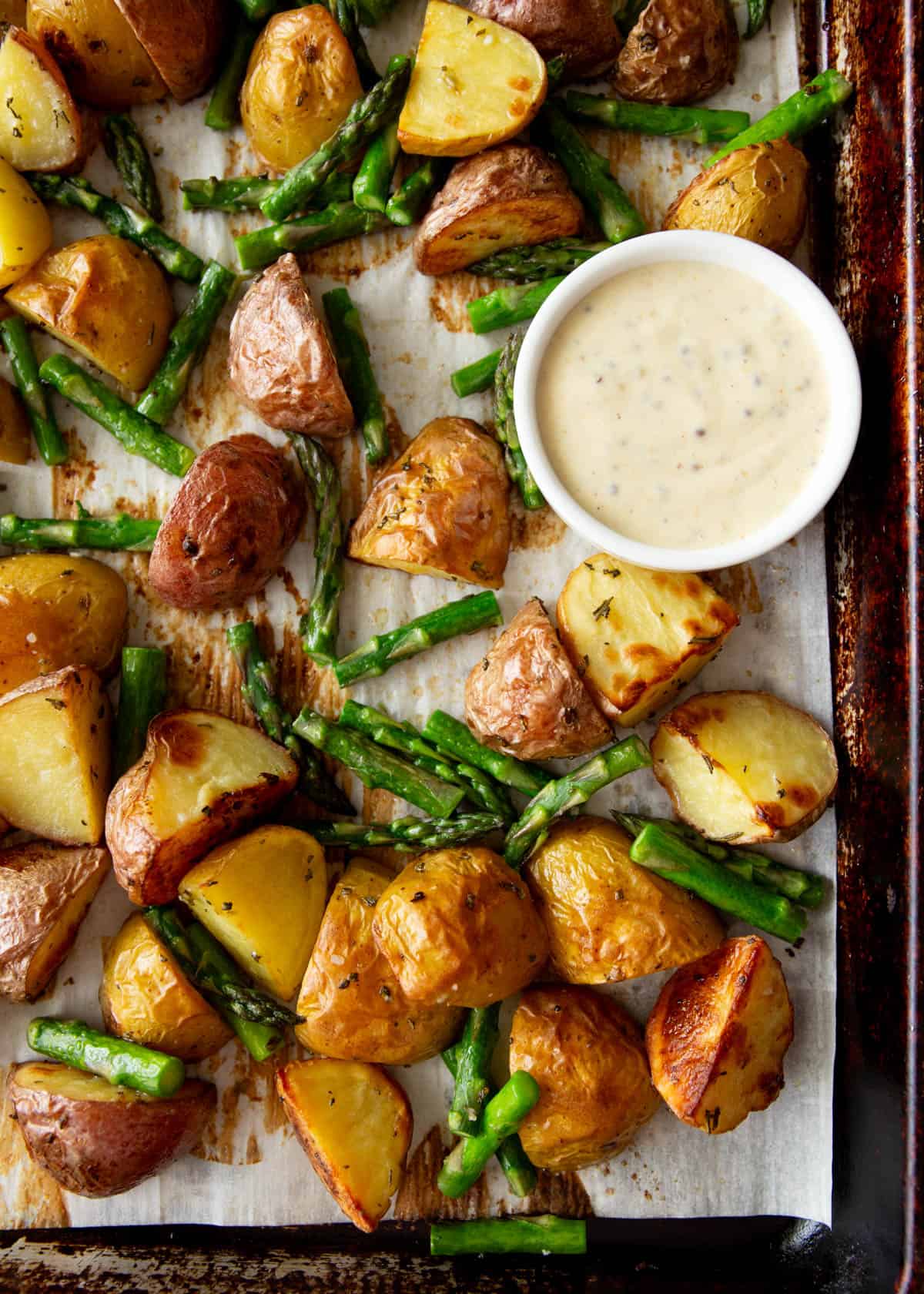 roasted asparagus and potatoes on a parchment lined sheet pan
