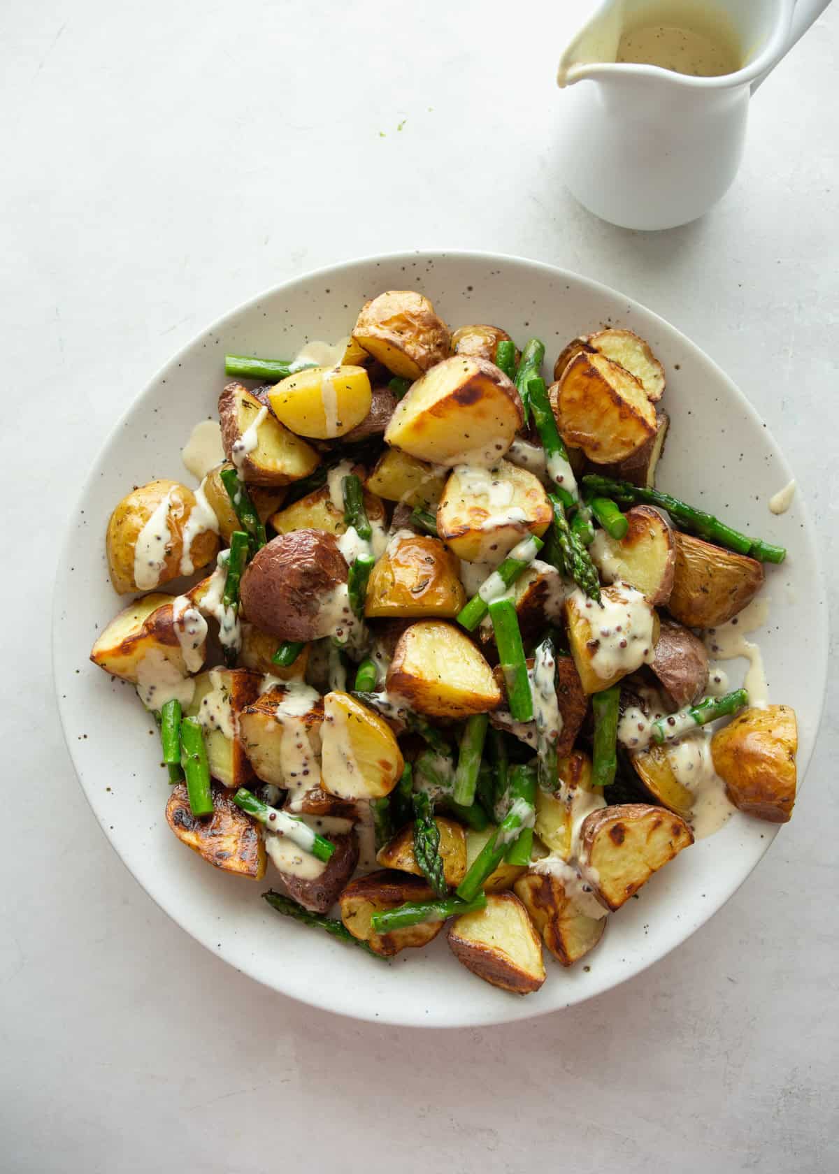 overhead image of roasted asparagus and potatoes in a white bowl
