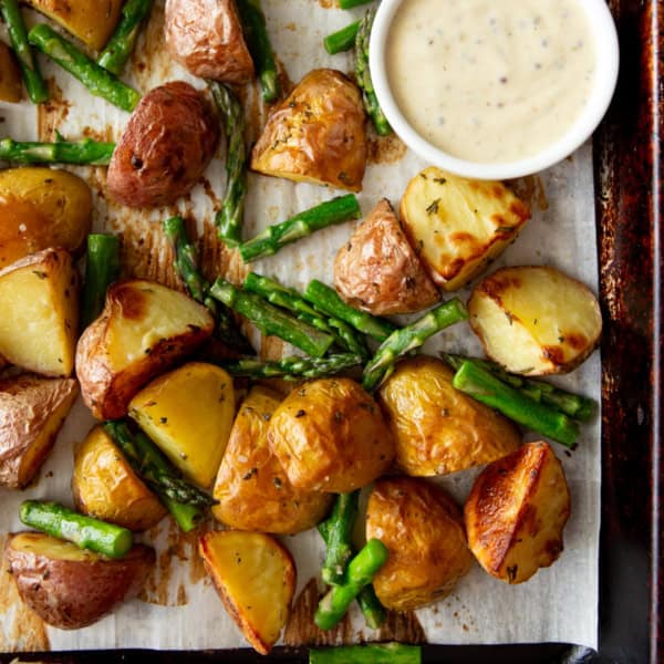 overhead image of roasted potatoes and asparagus on a parchment lined sheet pan