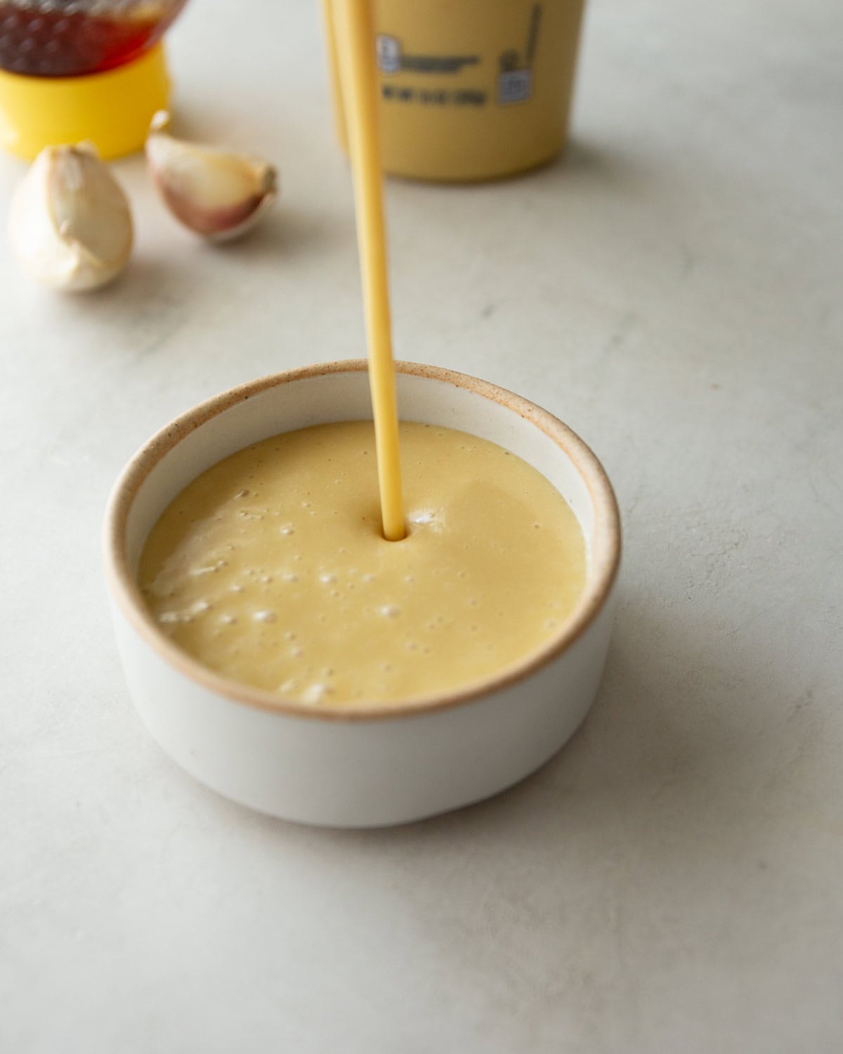 pouring honey dijon sauce into a small white bowl