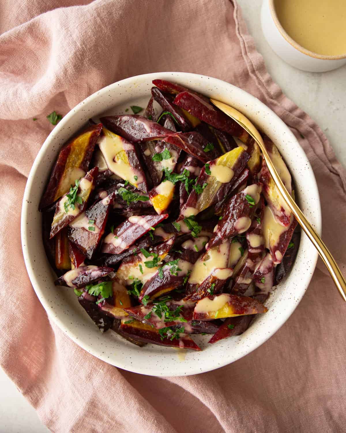 overhead image of roasted purple carrots in a white bowl