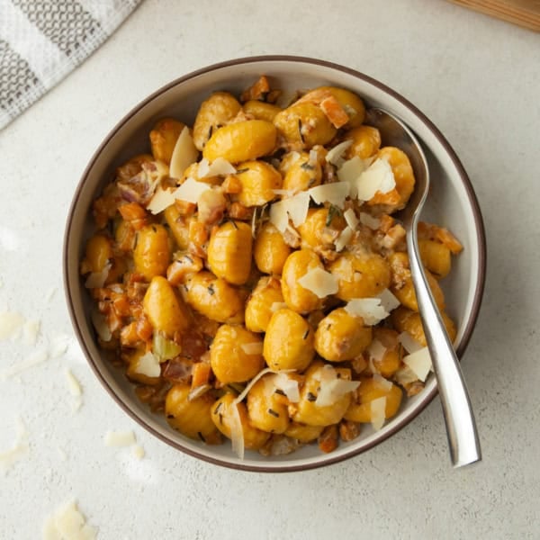 overhead image of pumpkin gnocchi in a white bowl with a spoon