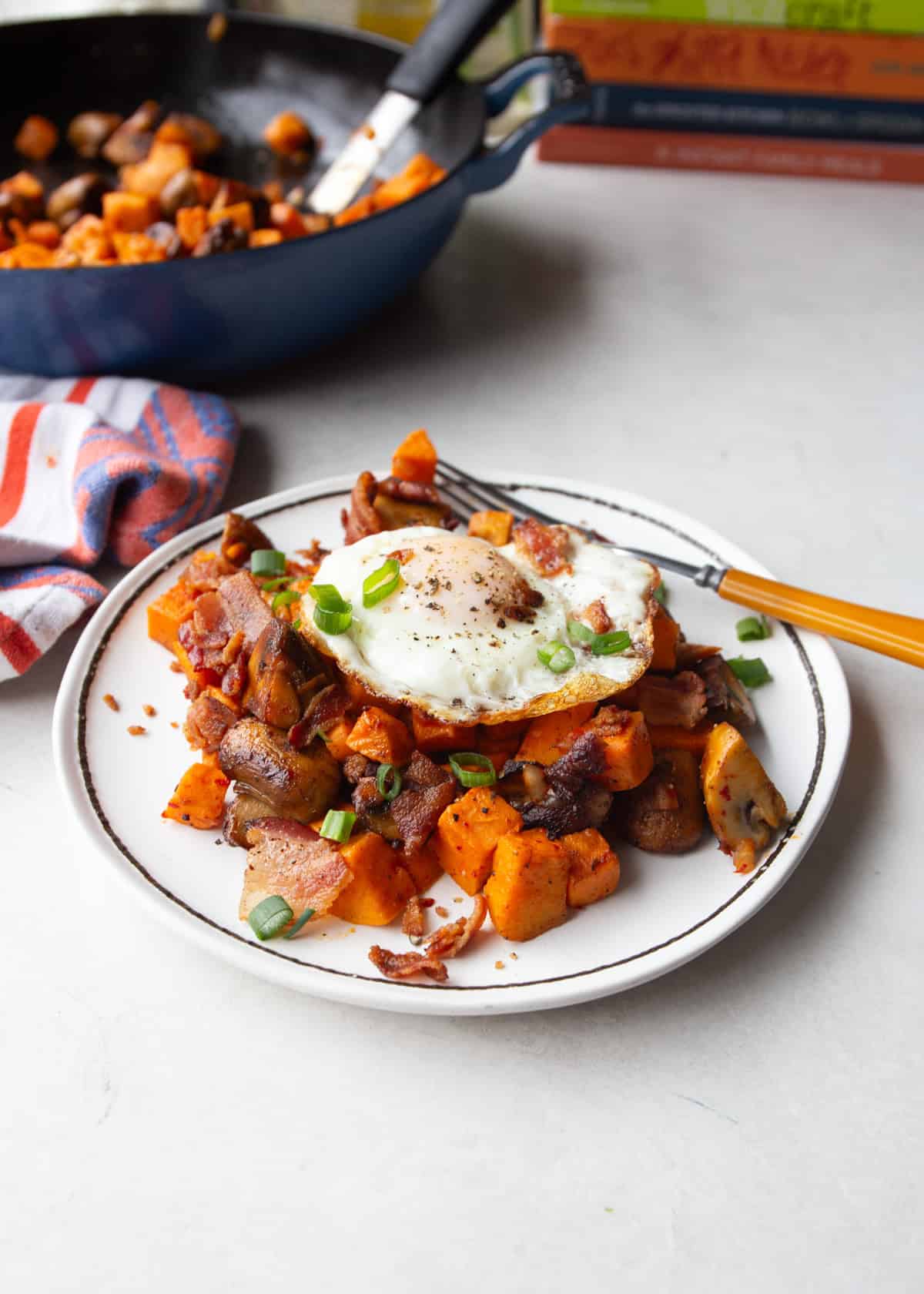 sweet potato hash topped with a fried egg on a white plate