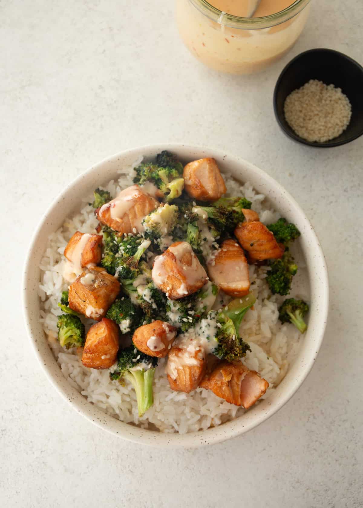 overhead image of broccoli and salmon bites over rice in a white bowl