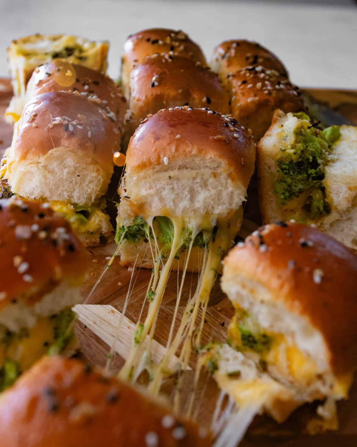 broccoli and cheese sliders on a wood cutting board