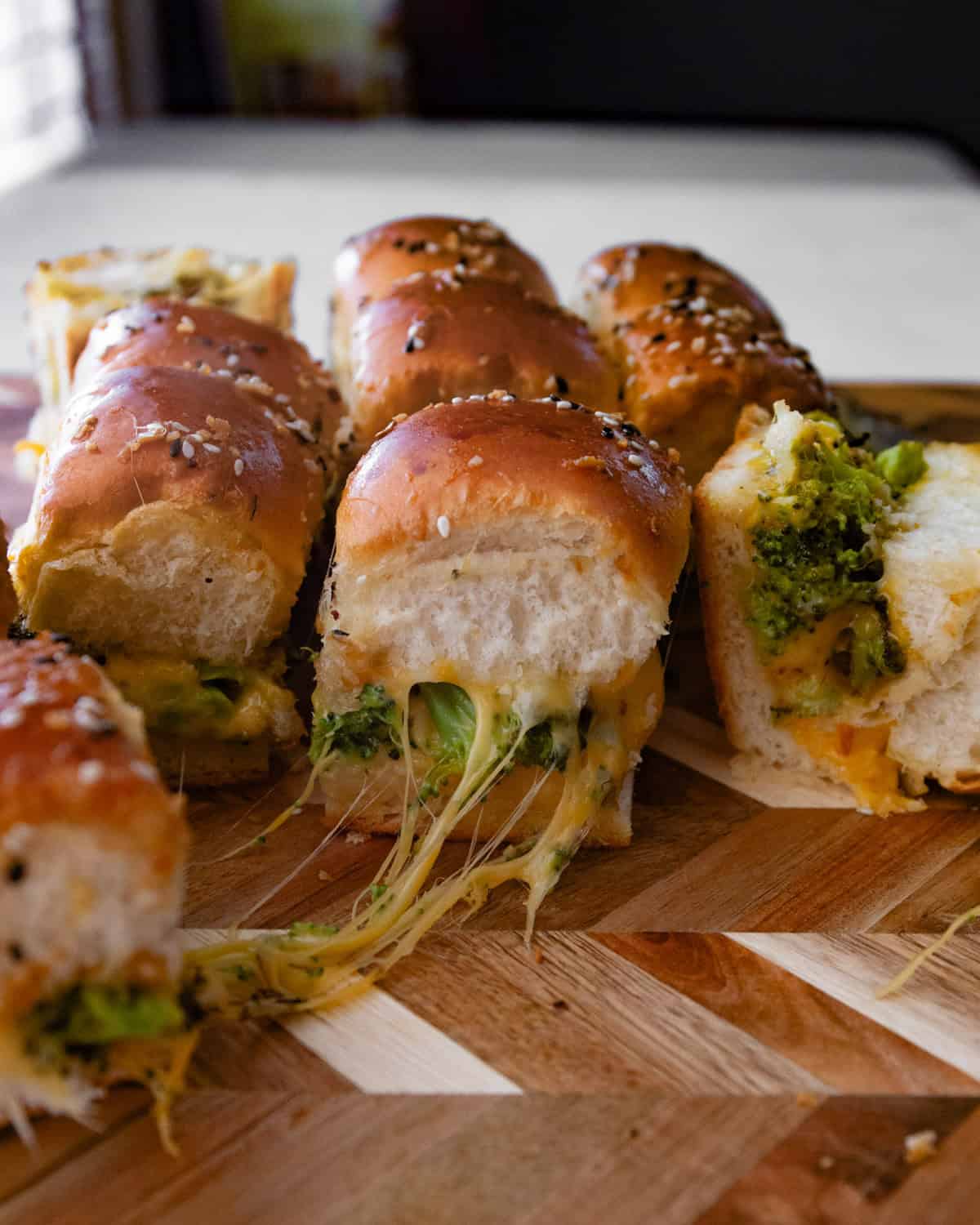 broccoli and cheese sliders on a wood cutting board