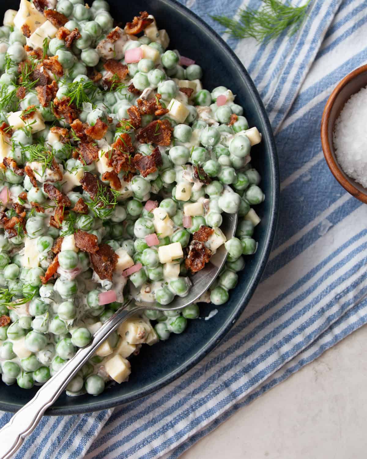 overhead image of a spoon in a black bowl of pea salad
