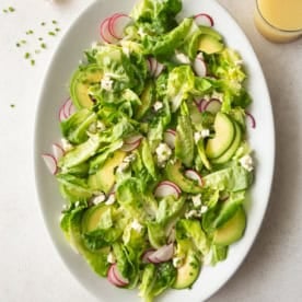 overhead image of butter lettuce salad on a white oval platter