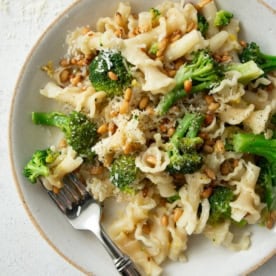 overhead image of broccoli pasta on a white plate with a fork