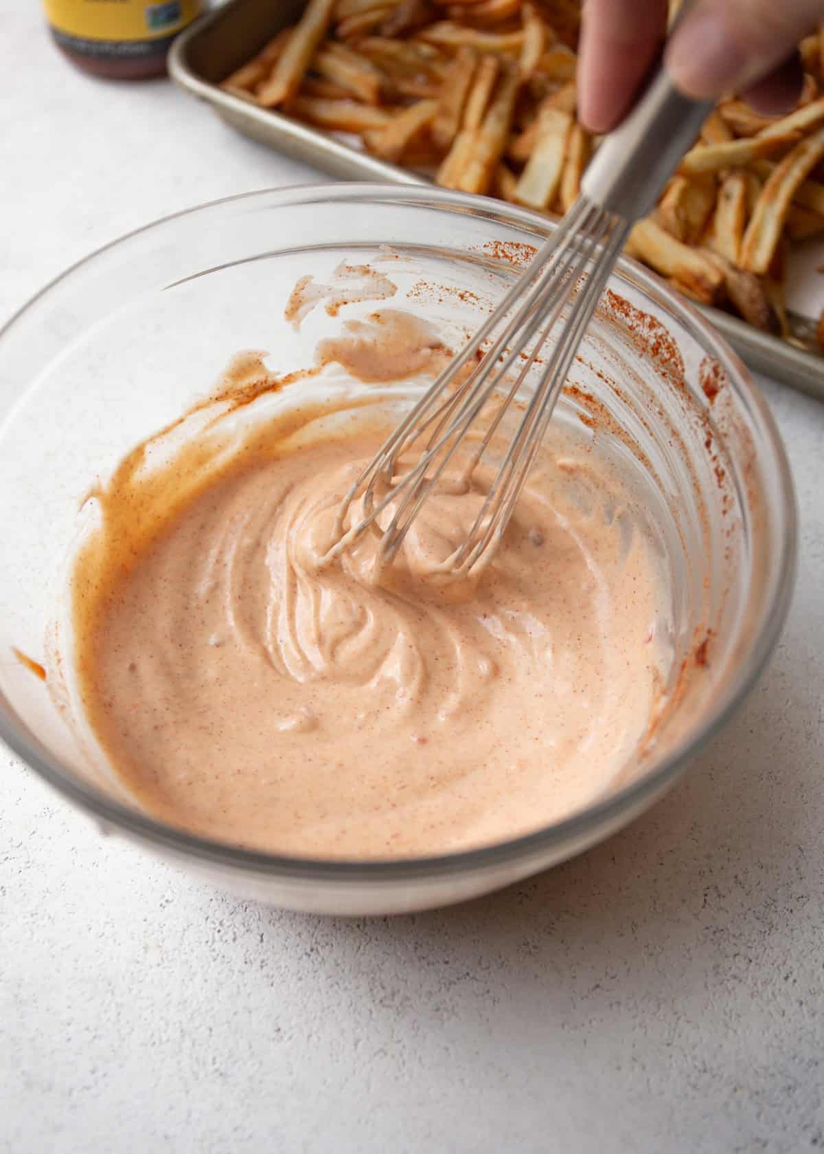 mixing yum yum sauce with a whisk in a clear glass bowl