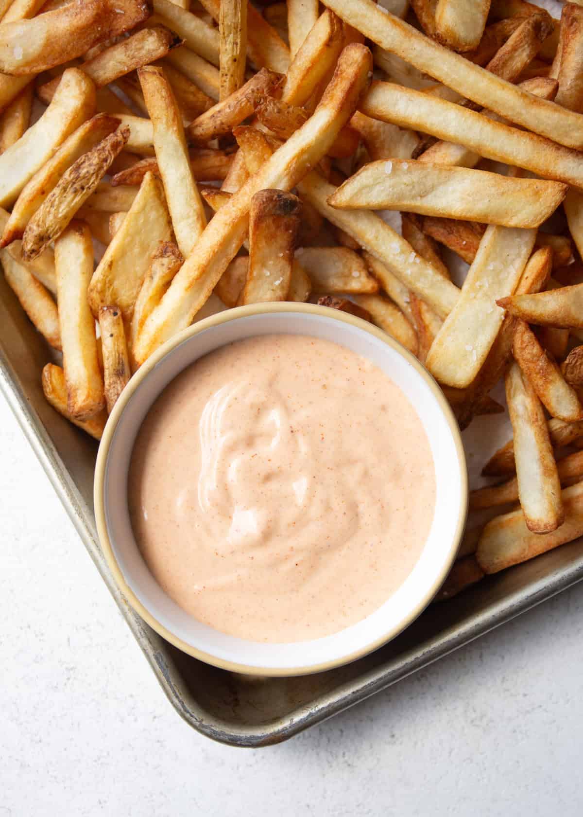 overhead image of french fries and sauce on a sheet pan