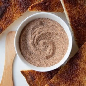 overhead image of cinnamon sugar in a white ramekin beside triangular pieces of cinnamon toast
