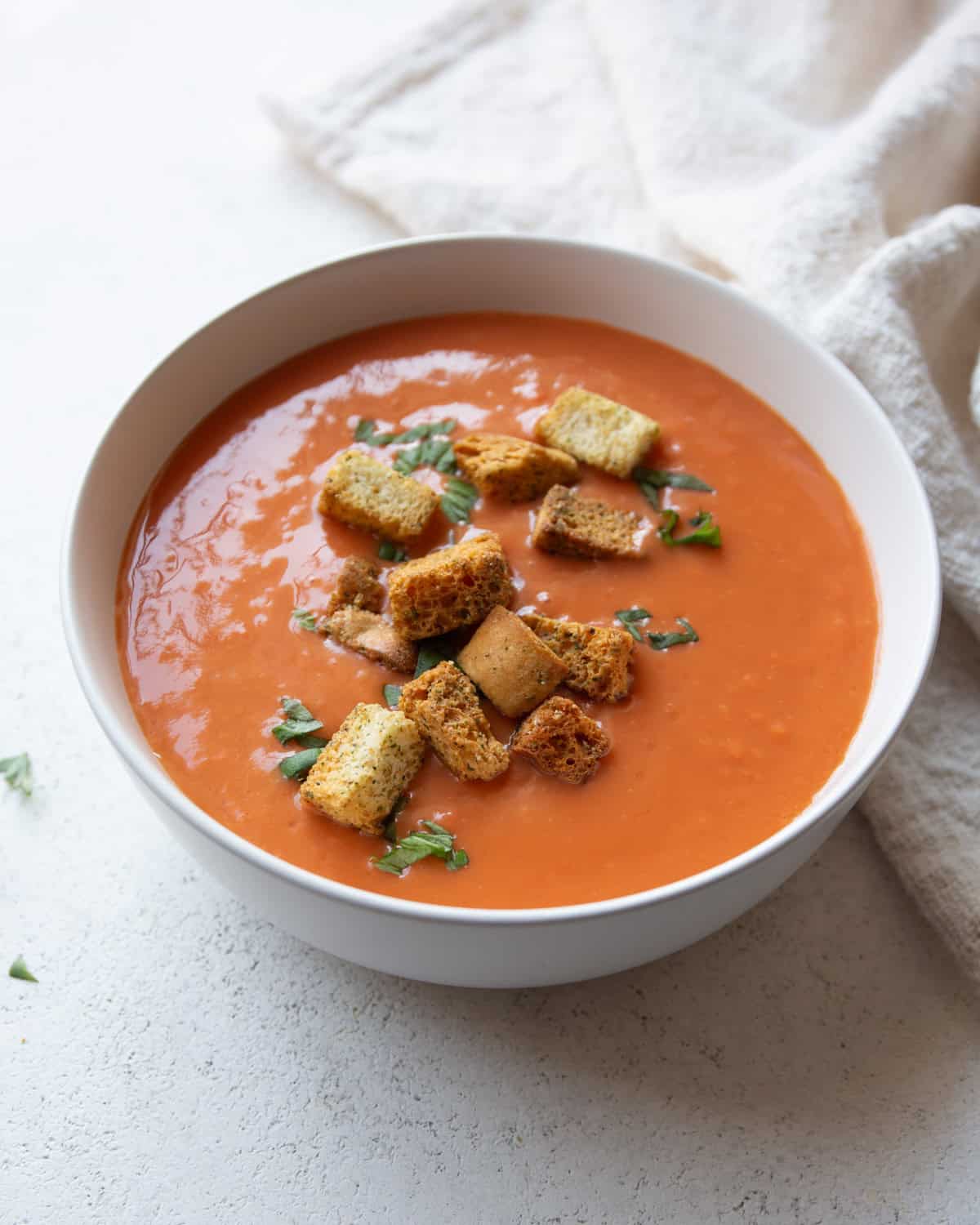 tomato soup topped with croutons in a white bowl