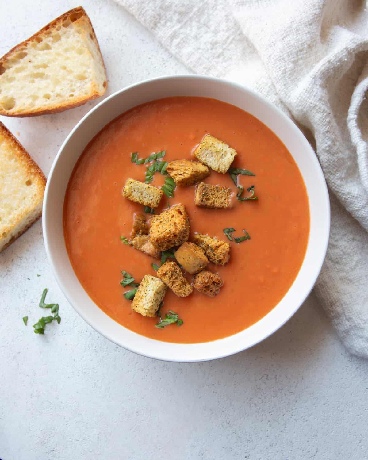 overhead image of tomato soup topped with croutons in a white bowl