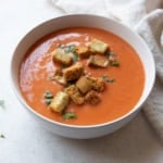 creamy tomato soup topped with croutons in a white bowl