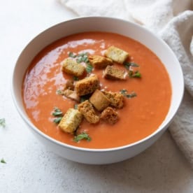 creamy tomato soup topped with croutons in a white bowl