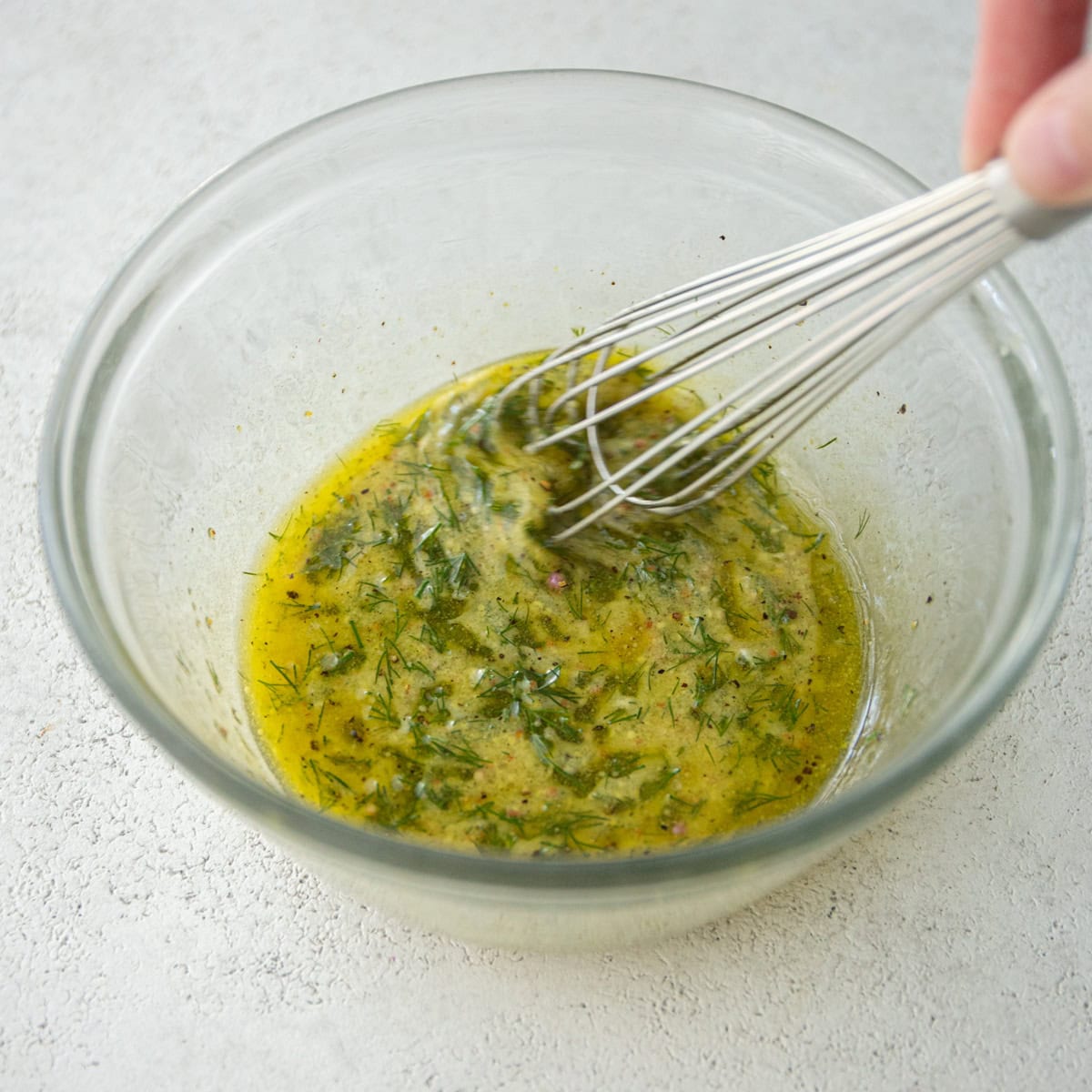 whisking dressing in a clear glass bowl