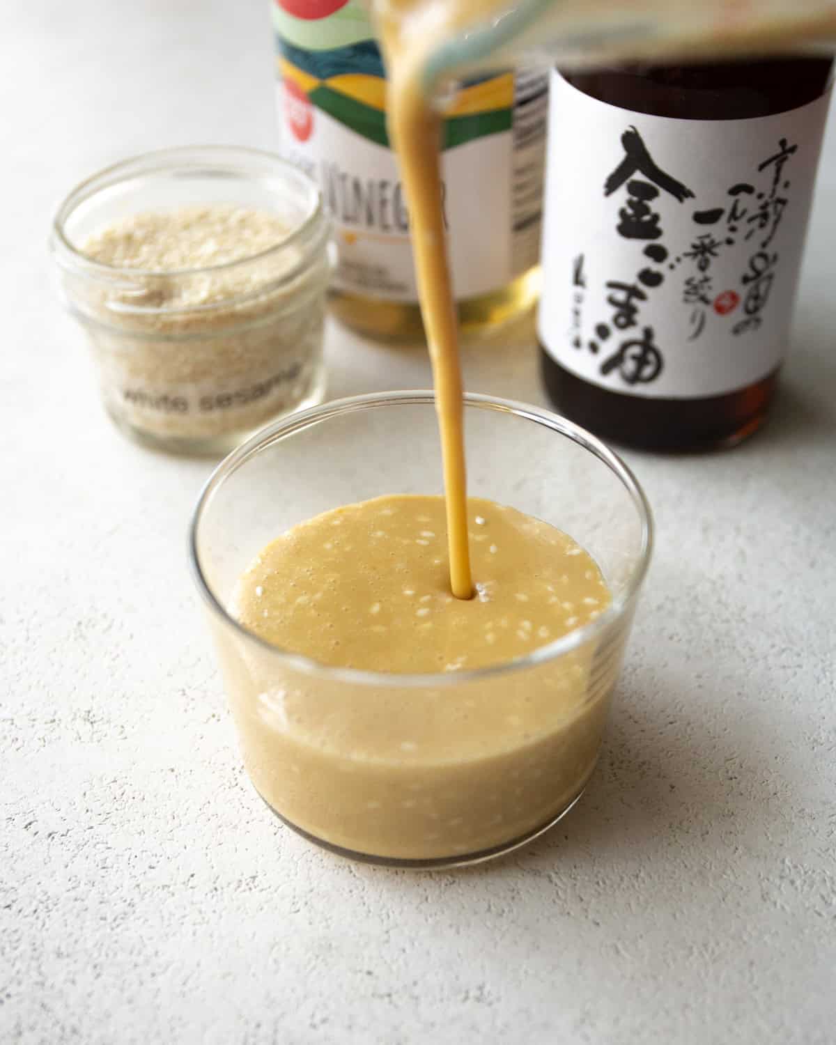 pouring miso salad dressing into a small glass ramekin