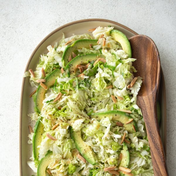 overhead image of salad on an oval plate with a wooden spoon