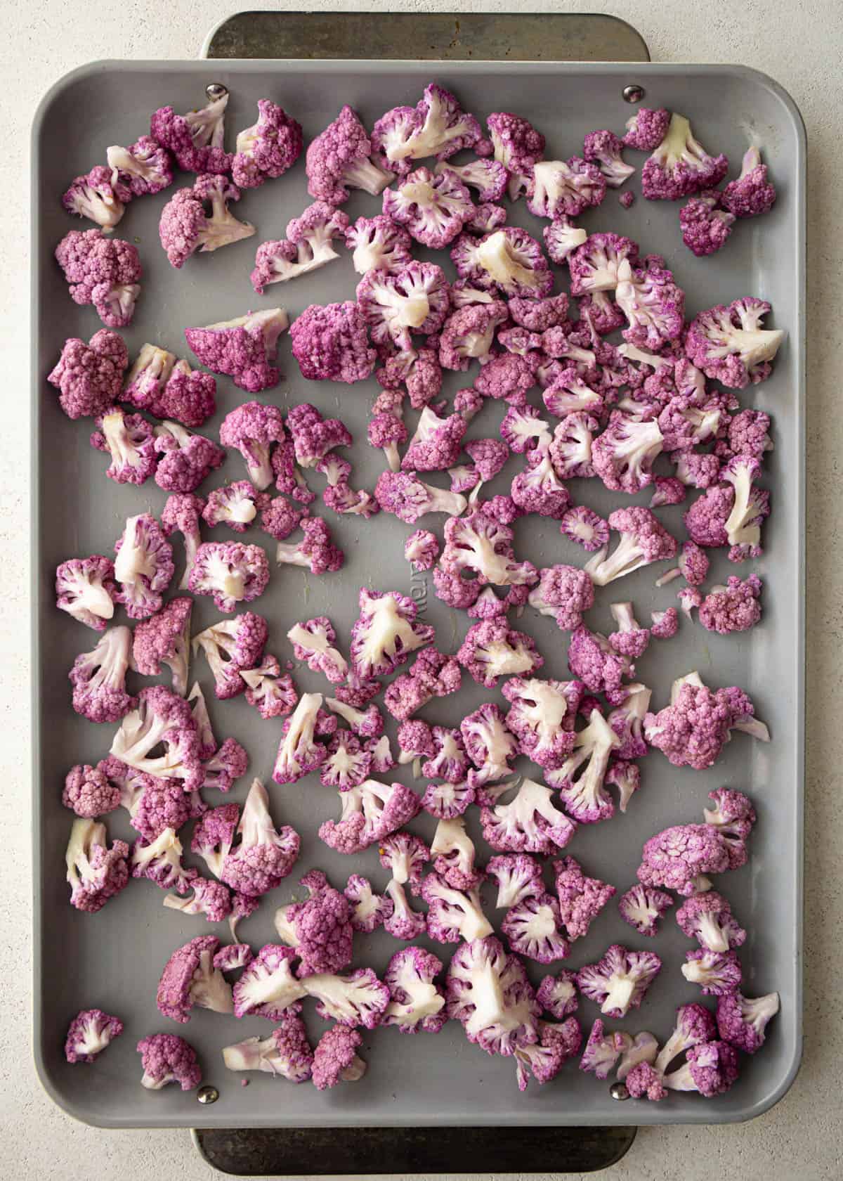 overhead image of raw purple cauliflower on a sheet pan