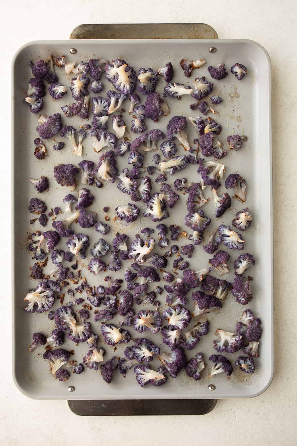 overhead image of roasted purple cauliflower florets on a sheet pan