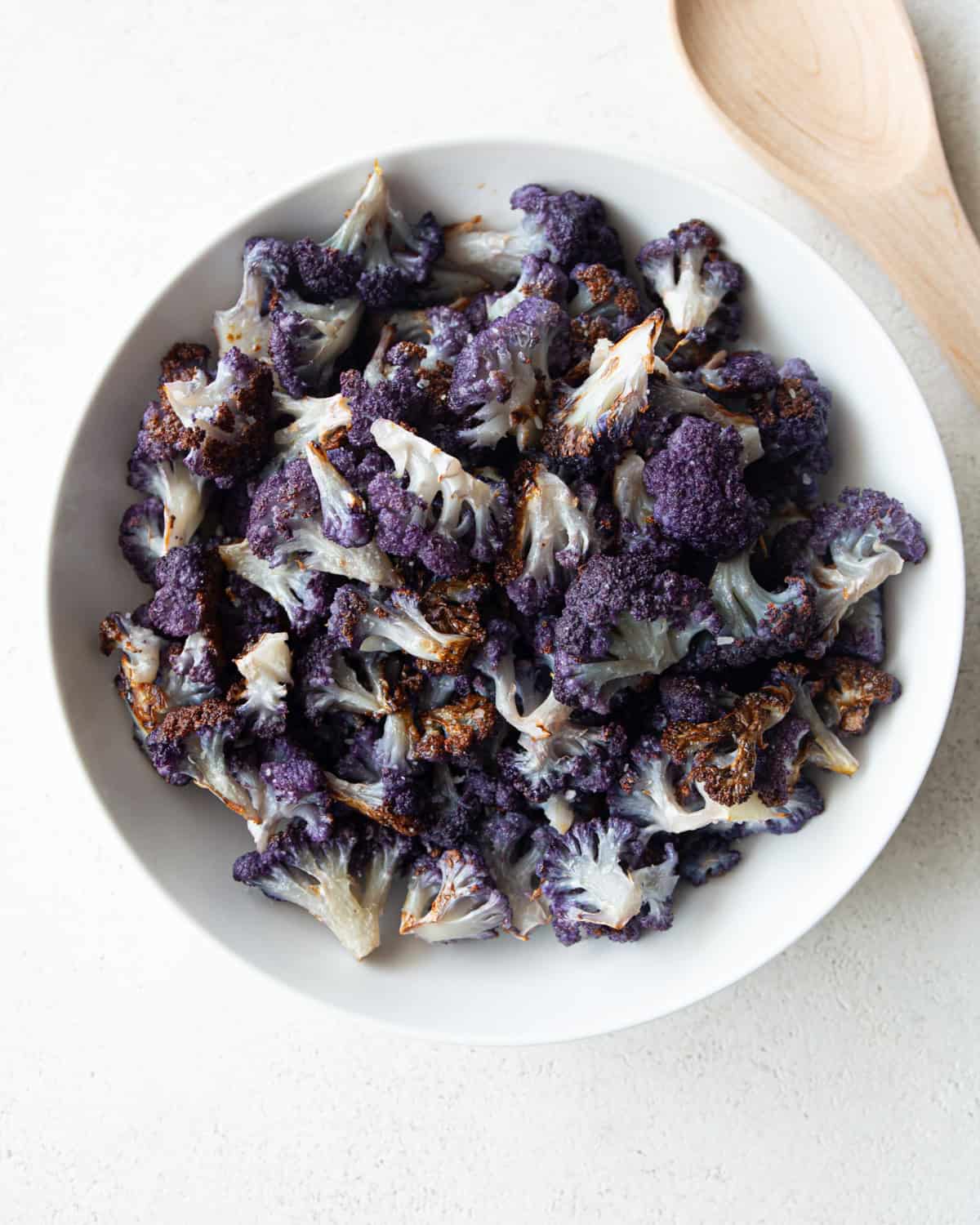 overhead image of roasted purple cauliflower in a white bowl
