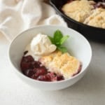 strawberry cobbler and a scoop of vanilla ice cream in a white bowl