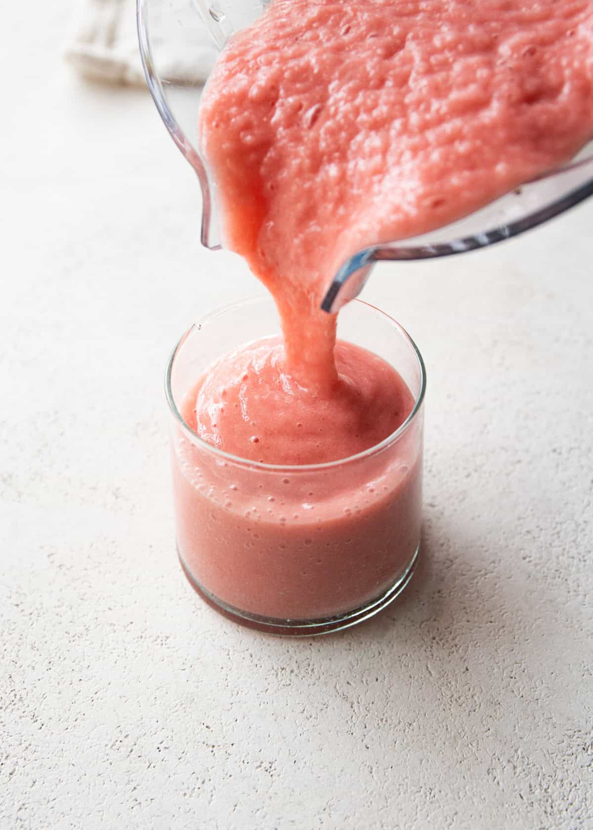 pouring strawberry pineapple smoothie into small glasses